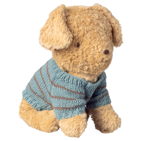 A fluffy, light brown teddy bear wears a blue, knitted sweater with brown stripes. Its expression is calm and endearing, against a white background.