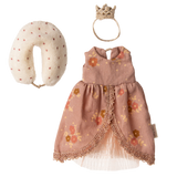 A floral pink doll dress with lace trim, a fabric crown, and a polka-dotted neck pillow are displayed on a white background. Elegant and playful.