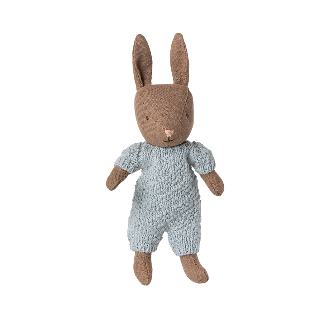 A plush brown bunny wearing a textured blue outfit, standing upright. The expression is neutral, with floppy ears and stitched details, conveying a cozy, handmade feel.