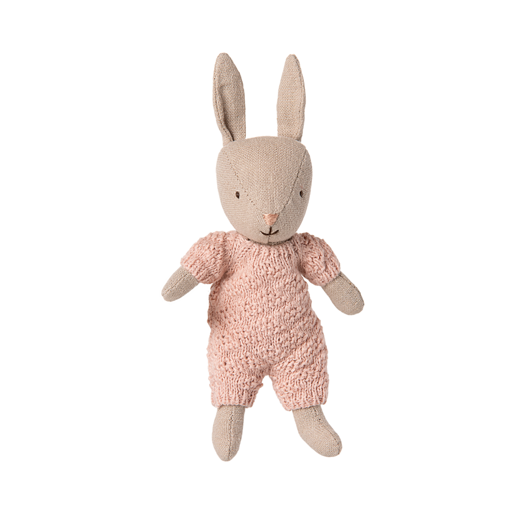 Cute fabric bunny doll in a knitted pink outfit. It has upright ears and a stitched face, conveying warmth and playfulness against a plain backdrop.