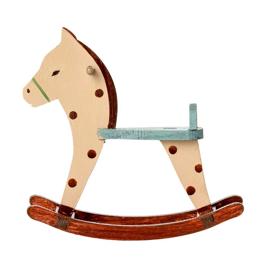 A vintage wooden rocking horse with a cream and brown design, featuring a green saddle and dark spots, sitting on curved wooden rockers.