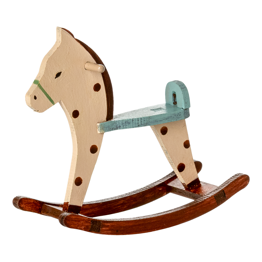 A vintage wooden rocking horse with a cream and brown design, featuring a green saddle and dark spots, sitting on curved wooden rockers.