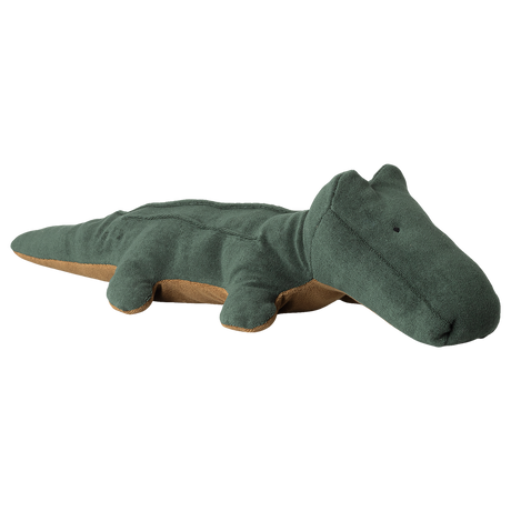 A soft, plush, green crocodile toy with a tan underside lies flat. The toy has a simple, friendly design, creating a playful and calming tone.
