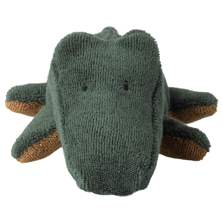 Close-up of a green plush crocodile on a white background, displaying a textured surface and simple, endearing facial features, conveying playfulness.