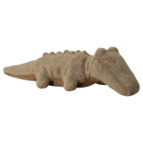 A plush crocodile toy with a beige, textured surface is shown on a white background. Its simple features convey a cozy, playful vibe.