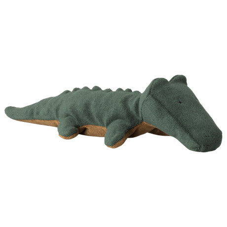 A soft, plush crocodile toy lies against a white background. The toy is dark green with a brown underside, featuring simple, stitched details.