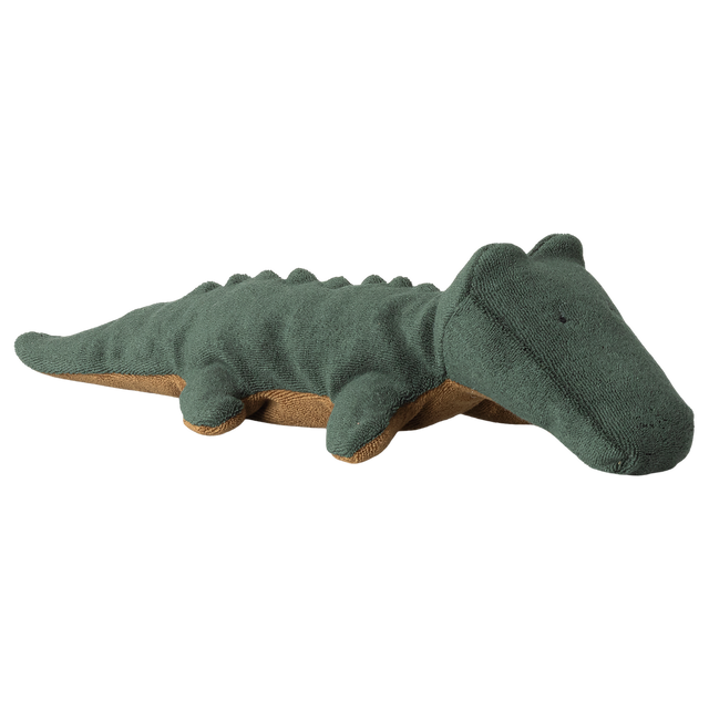 A soft, plush crocodile toy lies against a white background. The toy is dark green with a brown underside, featuring simple, stitched details.