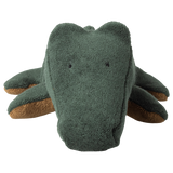 A plush crocodile toy with a textured, dark green surface and small, sewn eyes and smile. Its brown underbelly is visible. The image has a playful tone.