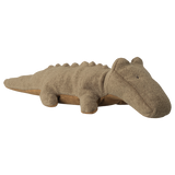 A soft, brown stuffed animal shaped like a crocodile lies against a white background. It has small eyes and a friendly, relaxed appearance.