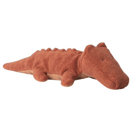 A soft, brown plush crocodile toy with a textured surface and small limbs, lying on a white background. The toy conveys a calm, friendly demeanor.