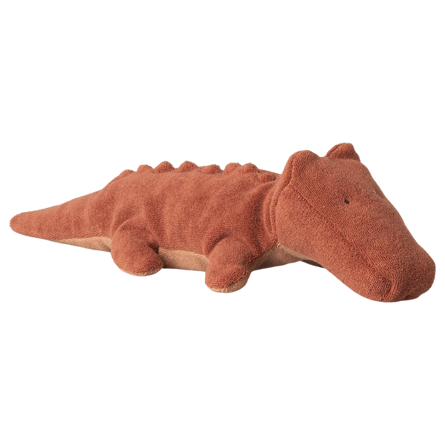 A soft, brown plush crocodile toy with a textured surface and small limbs, lying on a white background. The toy conveys a calm, friendly demeanor.