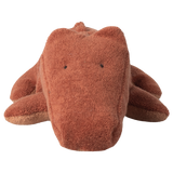 Brown plush crocodile toy with simple black eyes on a plain white background, conveying a cute and cuddly appearance.