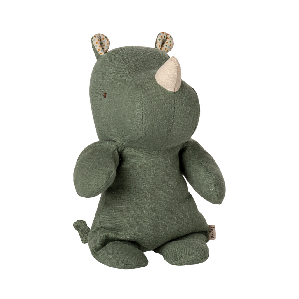 A plush green rhino toy with a soft horn sits upright on a plain background. Its ears have a polka dot inner pattern, and it exudes a calm, cozy vibe.
