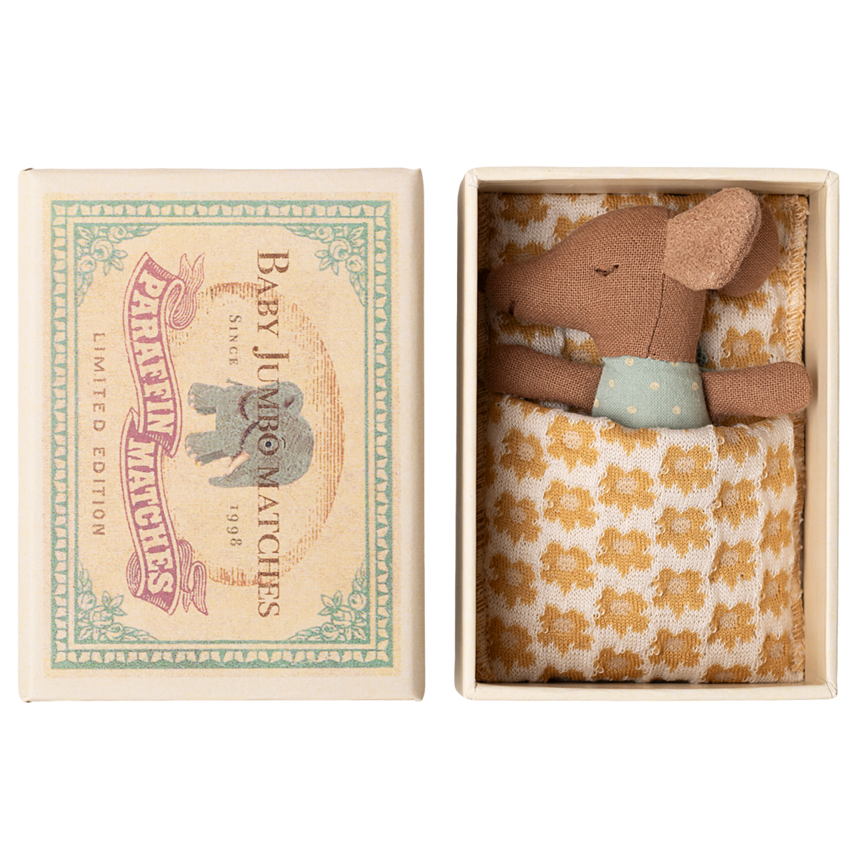A small brown stuffed mouse rests in an open box, nestled in a yellow-patterned blanket. The box lid features an illustration of an elephant and reads “Baby Jumbo Matches.”
