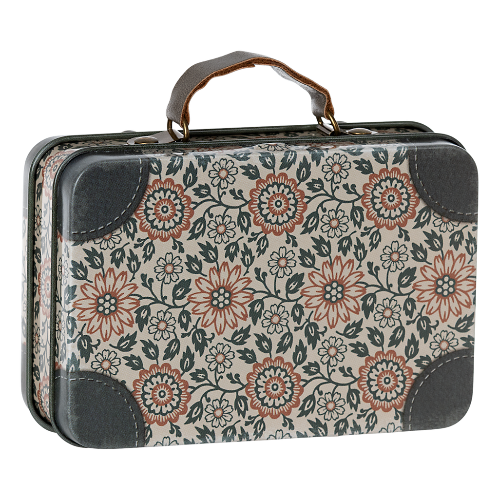 A floral-patterned vintage suitcase with a dark handle against a white background. The design features red and black flowers, creating a nostalgic, retro feel.