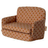 Miniature beige sofa with brown polka dots, featuring plush cushions and compact armrests. The playful design suggests a cozy, dollhouse ambiance.