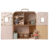 Dollhouse shaped like a suitcase, featuring mouse figurines. It has a cozy bedroom, a living area, and a kitchen, evoking a playful and quaint charm.