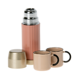 A stylish pink thermos with a gold lid and two matching pastel cups in white background.