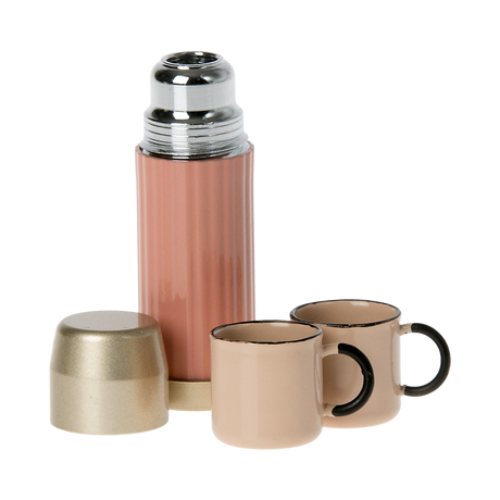 A stylish pink thermos with a gold lid and two matching pastel cups in white background.