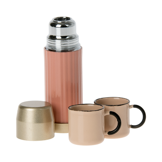 A stylish pink thermos with a gold lid and two matching pastel cups in white background.