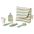 A striped pouch with tiny toiletries: a green shampoo bottle, a toothbrush, toothpaste, a hairbrush, and a collapsible cup on a white background.