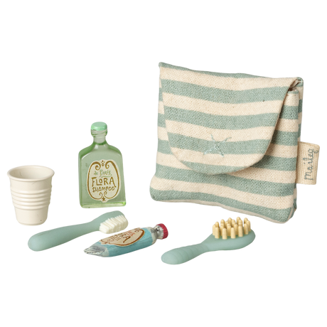 A striped pouch with tiny toiletries: a green shampoo bottle, a toothbrush, toothpaste, a hairbrush, and a collapsible cup on a white background.