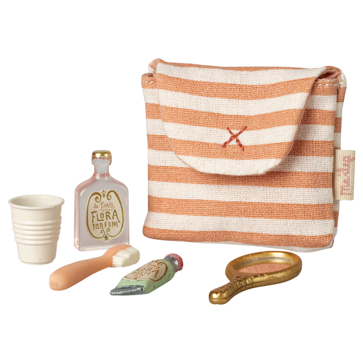 A small striped fabric pouch with a red cross is surrounded by a collection of miniature toiletries: a white cup, a perfume bottle, a toothbrush, a toothpaste tube, and a golden hand mirror, all against a white  background.