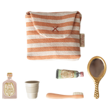 A small striped pouch and miniature items: two perfume bottles, a collapsible cup, a toothbrush, and a vintage-style hand mirror, arranged on a white background.