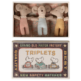 Three plush toy mice wearing red, blue, and yellow outfits lie in a decorative box labeled "TRIPLETS" with vintage-style graphics of mice driving cars.