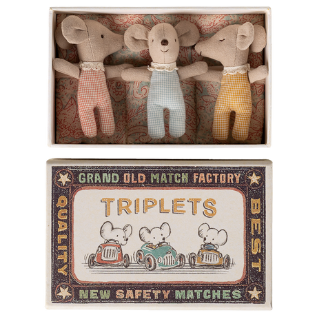 Three plush toy mice wearing red, blue, and yellow outfits lie in a decorative box labeled "TRIPLETS" with vintage-style graphics of mice driving cars.