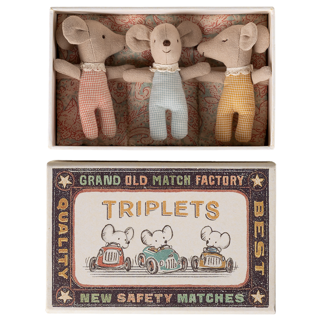 Three plush toy mice wearing red, blue, and yellow outfits lie in a decorative box labeled "TRIPLETS" with vintage-style graphics of mice driving cars.