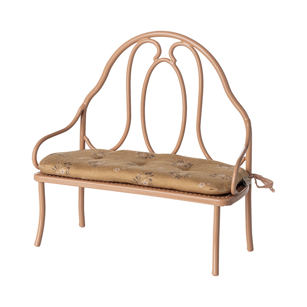 Vintage-style miniature wrought iron bench with a light brown, floral-patterned cushion. The elegant curves of the metal frame add a classic charm.