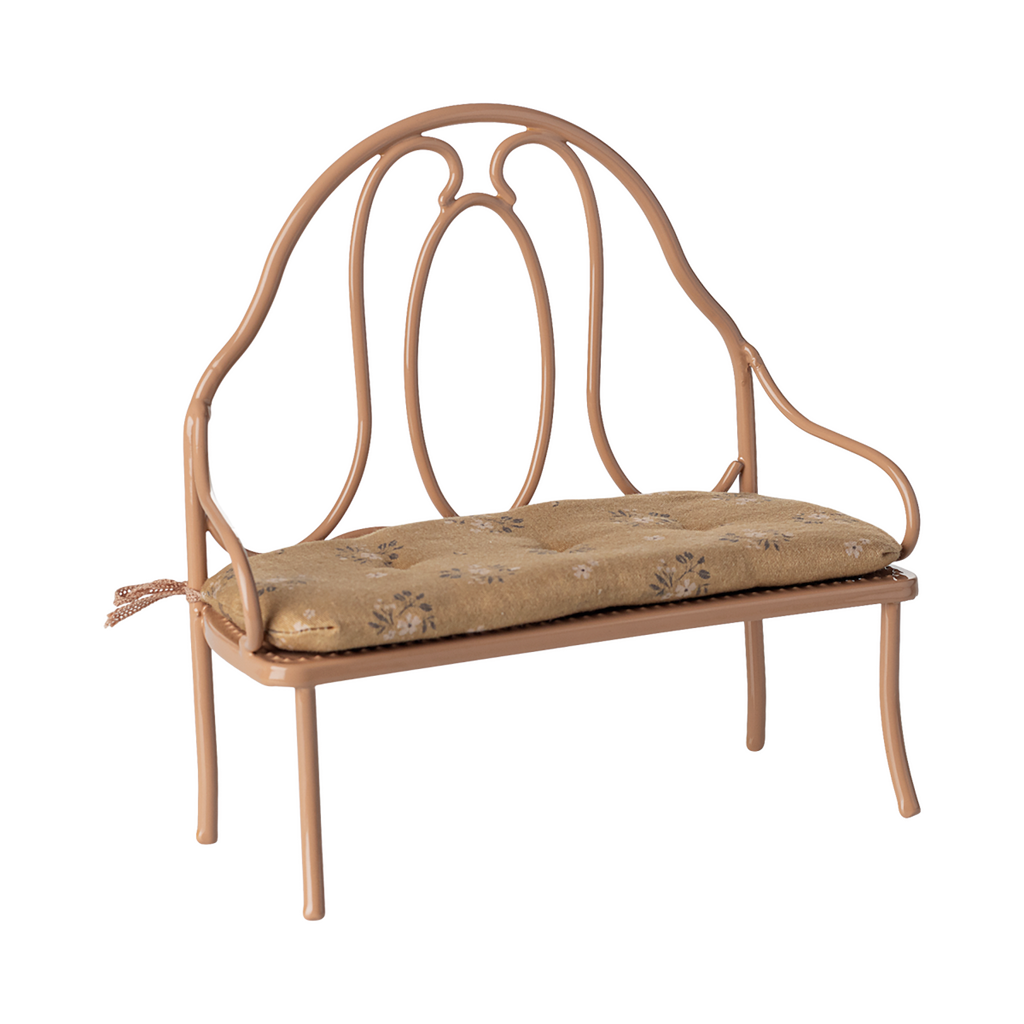 Vintage-style miniature wrought iron bench with a light brown, floral-patterned cushion. The elegant curves of the metal frame add a classic charm.