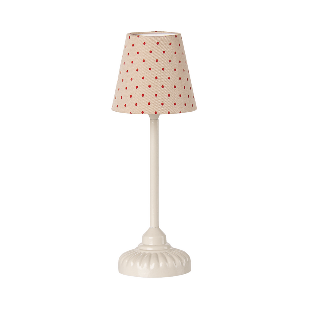 A miniature beige table lamp with a red polka dot shade and an ornate white ceramic base, creating a whimsical yet classic feel against a plain background.