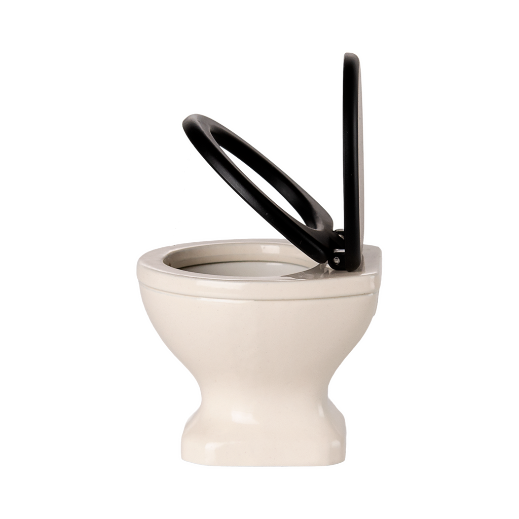 A miniature, white ceramic toilet with a black seat and lid open, set against a plain black background, conveying a quirky and playful tone.