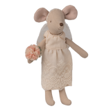 A small mouse doll wearing a lace dress and veil, holding a peach flower bouquet. The doll stands against a white background, evoking a whimsical tone.