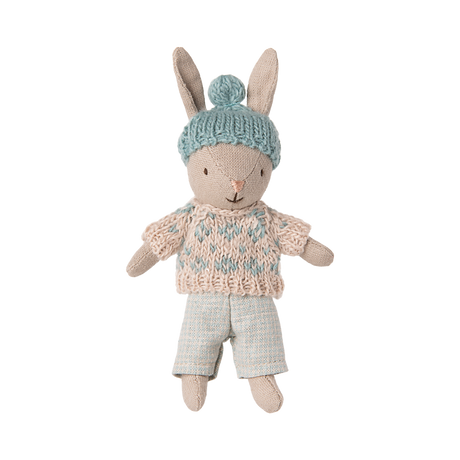 A plush rabbit toy wearing a knit blue hat with a pom-pom, a blue and beige sweater, and light blue pants, conveying a cozy and playful vibe.