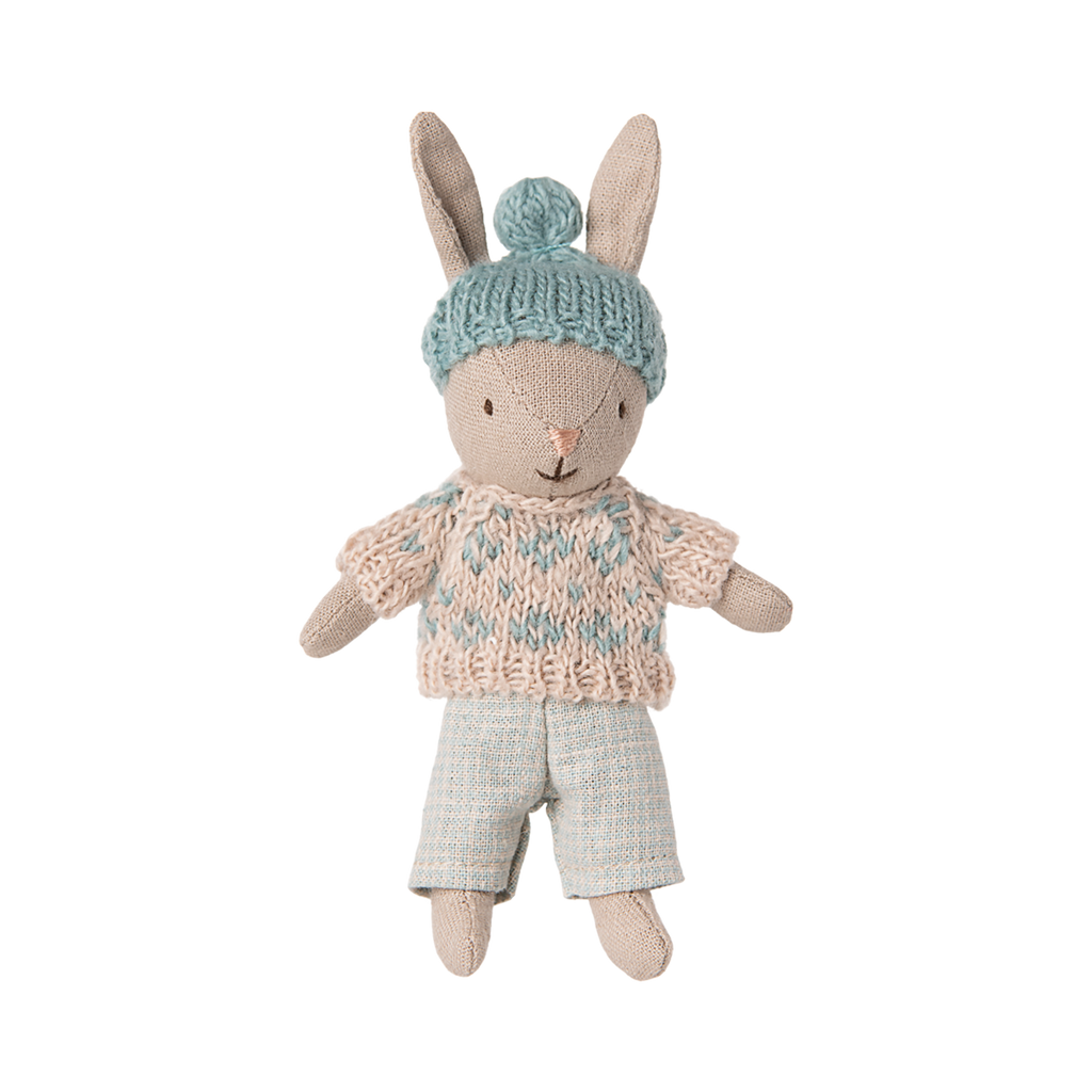 A plush rabbit toy wearing a knit blue hat with a pom-pom, a blue and beige sweater, and light blue pants, conveying a cozy and playful vibe.