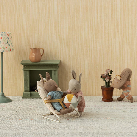 Maileg micro rabbits playing in a dollhouse room with a bouncer, ball, and watering can.