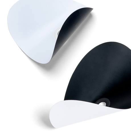 Close-up of black and white curved paper cutouts with grommet center holes against a white background.