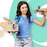 A smiling girl holding custom cardboard craft toys decorated with colorful paper twists and blue connectors.