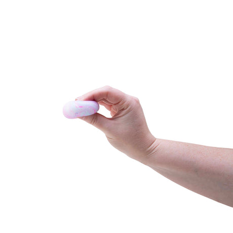 A hand pinches a small, pink and white marbled Swirl Teenie NeeDoh fidget toy against a solid white background.