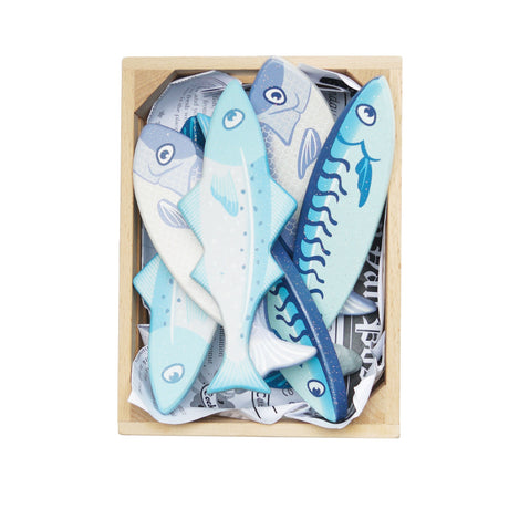 Top-down view of blue wooden play fish neatly packed in a crate with newspaper lining.
