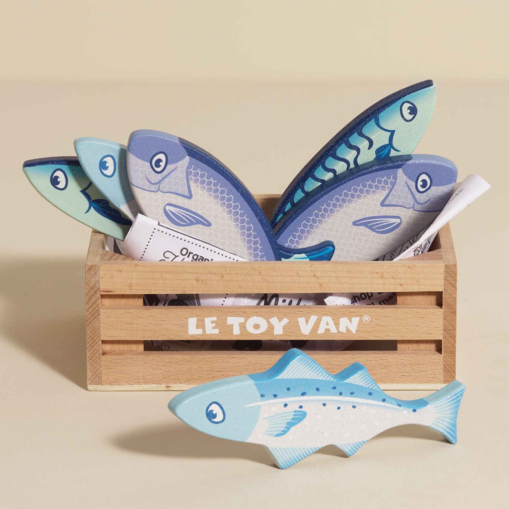 Wooden box with playful toy fish in blue tones. Fish feature simple smiling faces, conveying a cheerful and whimsical tone.