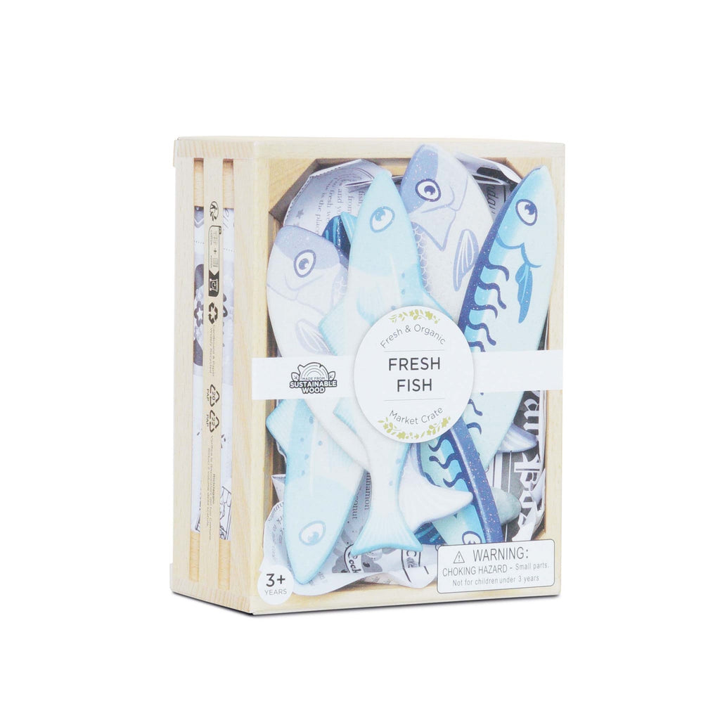 Wooden crate with blue and white toy fish labeled "Fresh Fish." Sustainable wood tag and choking hazard warning for ages 3 and up.