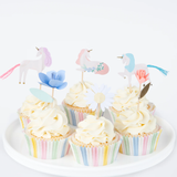 Group of decorated cupcakes with pastel striped liners, swirled white frosting, and unicorn and flower toppers.