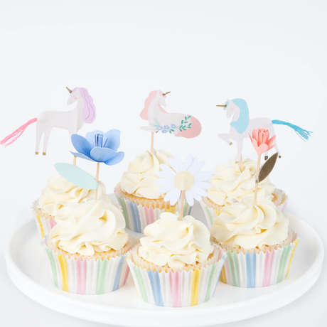 Group of decorated cupcakes with pastel striped liners, swirled white frosting, and unicorn and flower toppers.