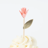 Pink flower cupcake topper with a gold leaf on a wooden pick, placed on swirled frosting.