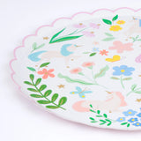A round paper plate with a pink scalloped edge, decorated with unicorns, flowers, and butterflies.