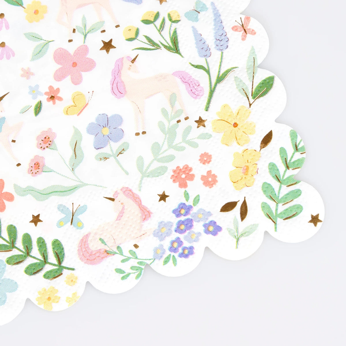 A white paper napkin with a scalloped edge, patterned with pastel unicorns, colorful flowers, and butterflies.